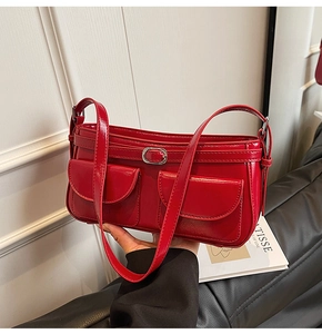 Détail du sac sous le bras en cuir verni rouge avec boucle argentée et doubles poches