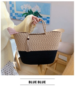 Detail of hand-woven straw tote with black contrast stripes and decorative wooden bead tassel