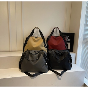 Detail view of large travel bags in khaki, burgundy, grey and black with wide straps
