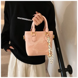 Detail of pink glossy leather handbag with gold hardware and striped silk scarf wrap