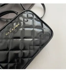 Gros plan sur un petit sac carré noir matelassé avec logo doré et finition brillante
