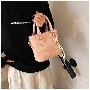 Pink patent leather handbag detail featuring a decorative black and white silk scarf handle