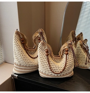 Detail of hand-woven straw hobo bag with wooden bead straps and brown base stripes