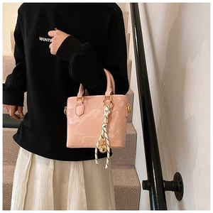 Detail of pink marble textured bucket bag with woven rope charm and golden logo