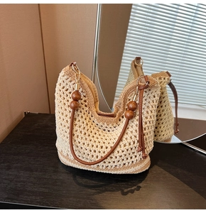 Close-up of crochet hollow weave bag with wooden bead decor and brown leather handle