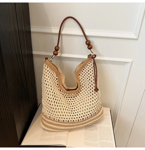 Close-up of beige woven shoulder bag with dark wood beads and brown striped base detail