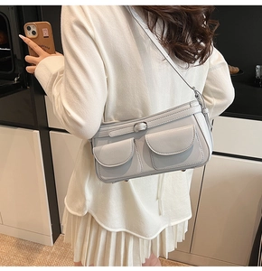 Modèle portant un sac à bandoulière bleu-gris clair avec poches doubles et boucle en métal