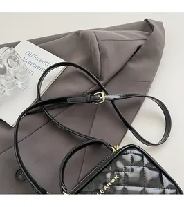Détail du sac à bandoulière en cuir noir matelassé avec logo doré sur costume