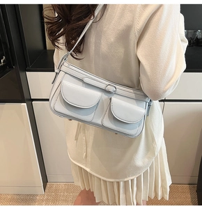 Détail d'un sac sous le bras bleu clair avec deux poches avant et boucles en argent