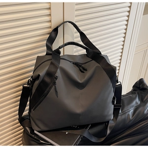 Detail of dark grey waterproof nylon travel bag with crossbody strap and double handles