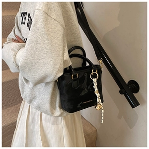 Detail of black glossy bucket bag featuring marble texture and a striped silk scarf handle
