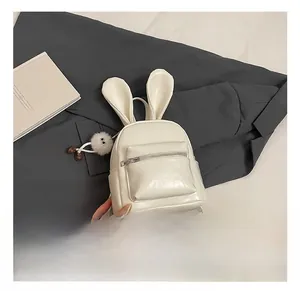 Close-up of a white leather mini backpack featuring cute bunny ears and a plush pompom charm