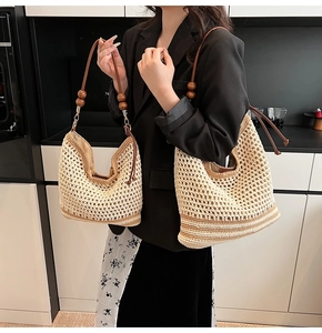 Detail of hollow woven straw tote bag with wooden beads and brown stripe base