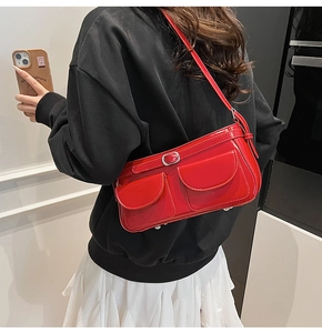 Détail du sac à bandoulière en cuir verni rouge vif avec poches frontales et boucles argentées
