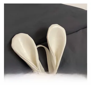 Detail of white PU leather backpack featuring cute bunny ears and soft pompom charm