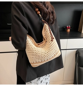 Detail of woven beige hobo bag with dark brown leather strap and large wooden beads