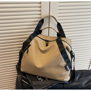 Detailed side view of khaki waterproof travel tote bag with black straps on leather surface