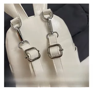 Macro shot of silver metal buckles and adjustable straps on a white PU leather backpack