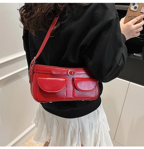 Détail du sac à bandoulière en cuir rouge avec doubles poches et boucles argentées
