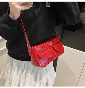 Détail du sac à bandoulière rouge avec poches frontales et boucle en métal argenté