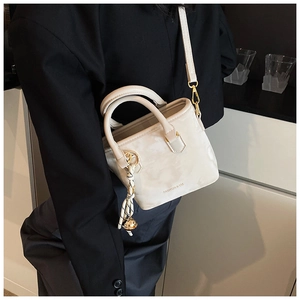 Chic cream leather bucket bag with top handles and logo detail worn with black suit