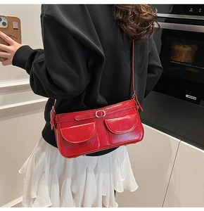 Détail du sac bandoulière en cuir verni rouge brillant avec doubles poches et boucles argent