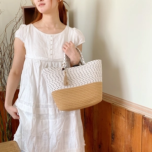 Detail of woven tote bag with polka dot pattern and wooden tassel charm in a home setting