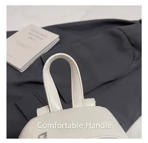Close-up of comfortable top handle and reinforced stitching on off-white backpack