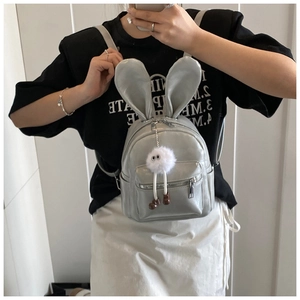 Mini light grey backpack with bunny ears and a cute plush ball charm on a person