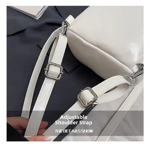 Detail of adjustable white leather straps with silver metal buckles and swivel hooks