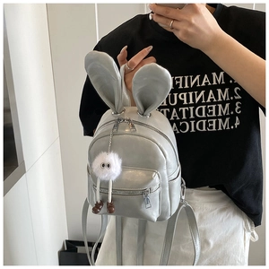Detail of silver faux leather mini backpack featuring cute bunny ears and fluffy charm