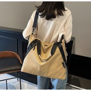 Detail of khaki and black crossbody tote bag showing side zipper and adjustable strap
