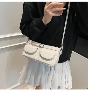 Détail du sac à bandoulière crème avec deux poches avant et des boucles métalliques élégantes