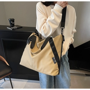 Detail of khaki waterproof tote bag with black wide straps shown on a female model