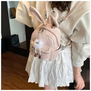 Detail of pink faux leather mini backpack with cute rabbit ears and plush charm