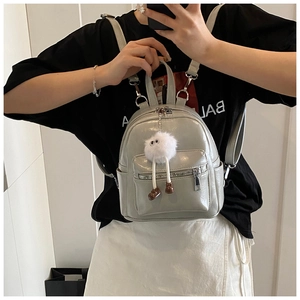 Close-up of a stylish grey mini backpack featuring a cute white plush monster keychain charm