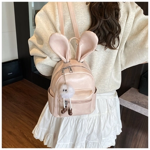 Detail of pink faux leather backpack with bunny ears and a plush eyeball charm