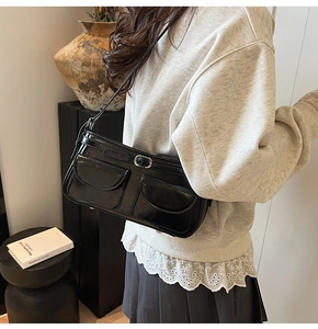 Détail du sac sous le bras noir brillant avec boucles et poches avant symétriques