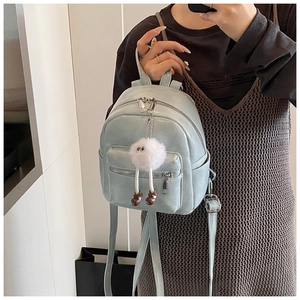 Close-up of a light blue mini PU leather backpack with silver zippers and plush charm