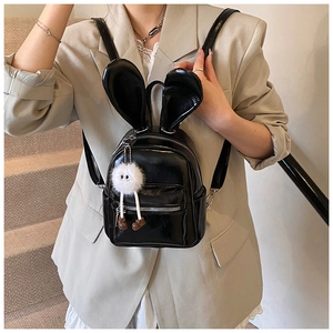 Detail of black glossy PU backpack featuring bunny ears and a white plush mascot charm