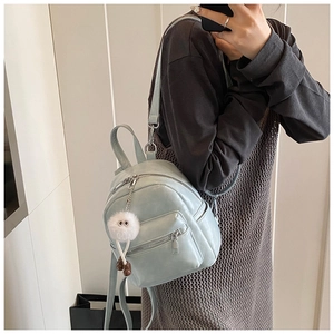 Close-up of a mini light blue backpack with a plush charm and adjustable shoulder straps