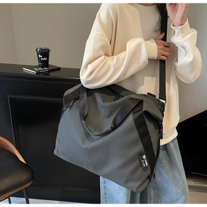 Detail view of large grey nylon travel tote bag with adjustable shoulder strap and logo
