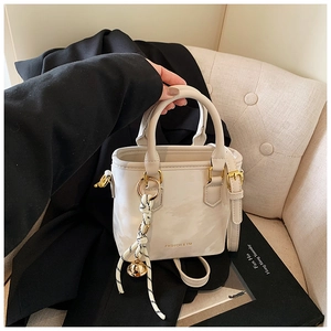 Close-up of cream PU leather handbag with silk scarf charm and gold metal ring detail