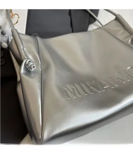 Close-up of silver PU leather tote bag with MIKAXIO embossed logo and knot detail