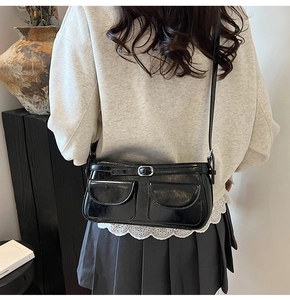 Détail d'un sac d'épaule noir en similicuir avec deux poches avant et boucles argentées