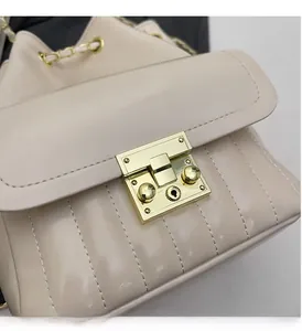 Dettaglio borsa a secchiello trapuntata beige con chiusura dorata e tracolla a catena
