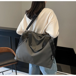 Detailed shot of large dark grey travel tote bag showing adjustable shoulder strap and texture
