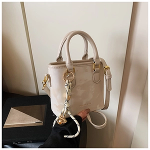 Detailed view of the beige mini bucket bag with gold hardware and striped rope charm