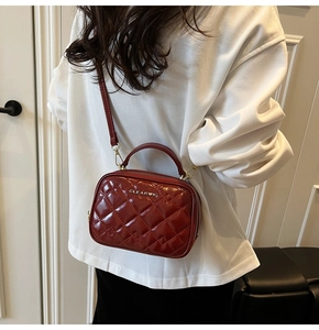 Détail du sac bandoulière matelassé bordeaux avec poignée en métal et fini brillant