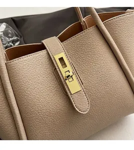 Dettaglio della borsa tote in pelle beige con trama litchi e chiusura a girello dorata